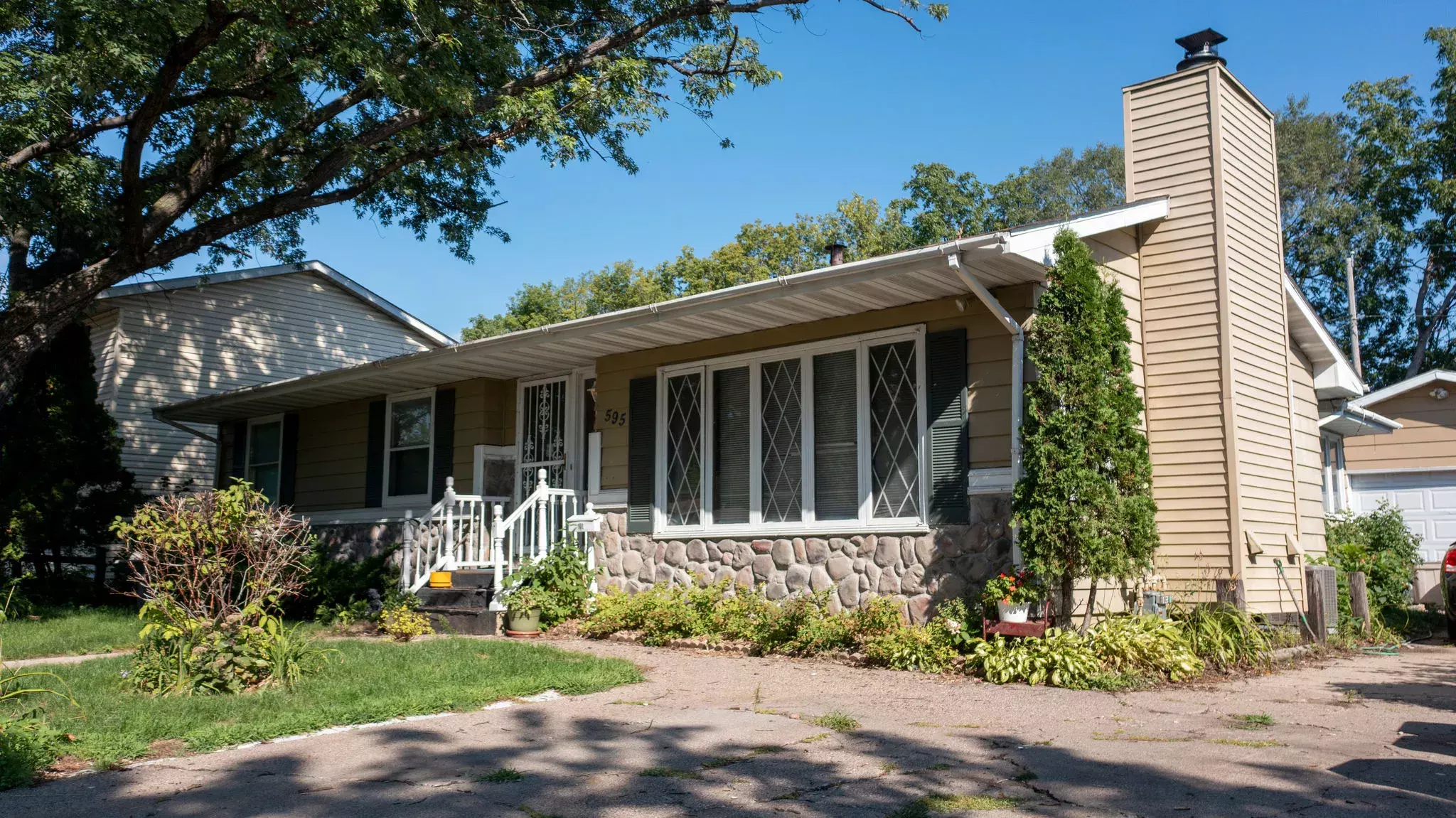 Rambler home in a residential neighborhood with greenery out front.