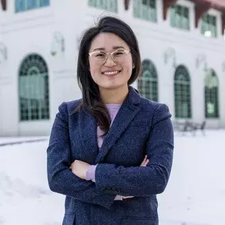 Ward 5 councilmember elect Hwa Jeong Kim stands smiling in front of the Como Pavilion in winter.