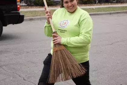 a woman being goofy, posting with a rake