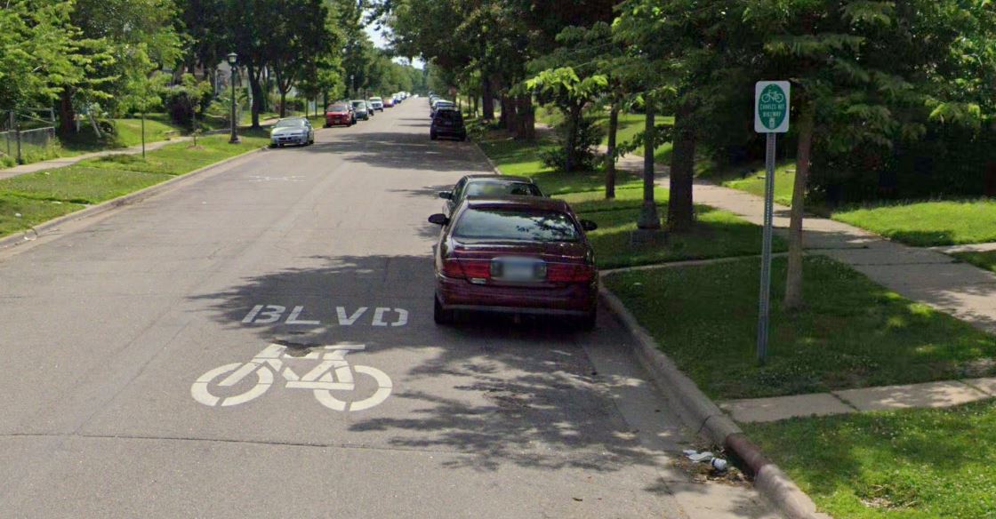 Street with paint on it saying boulevard and a bike image and a street sign naming the bike boulevard