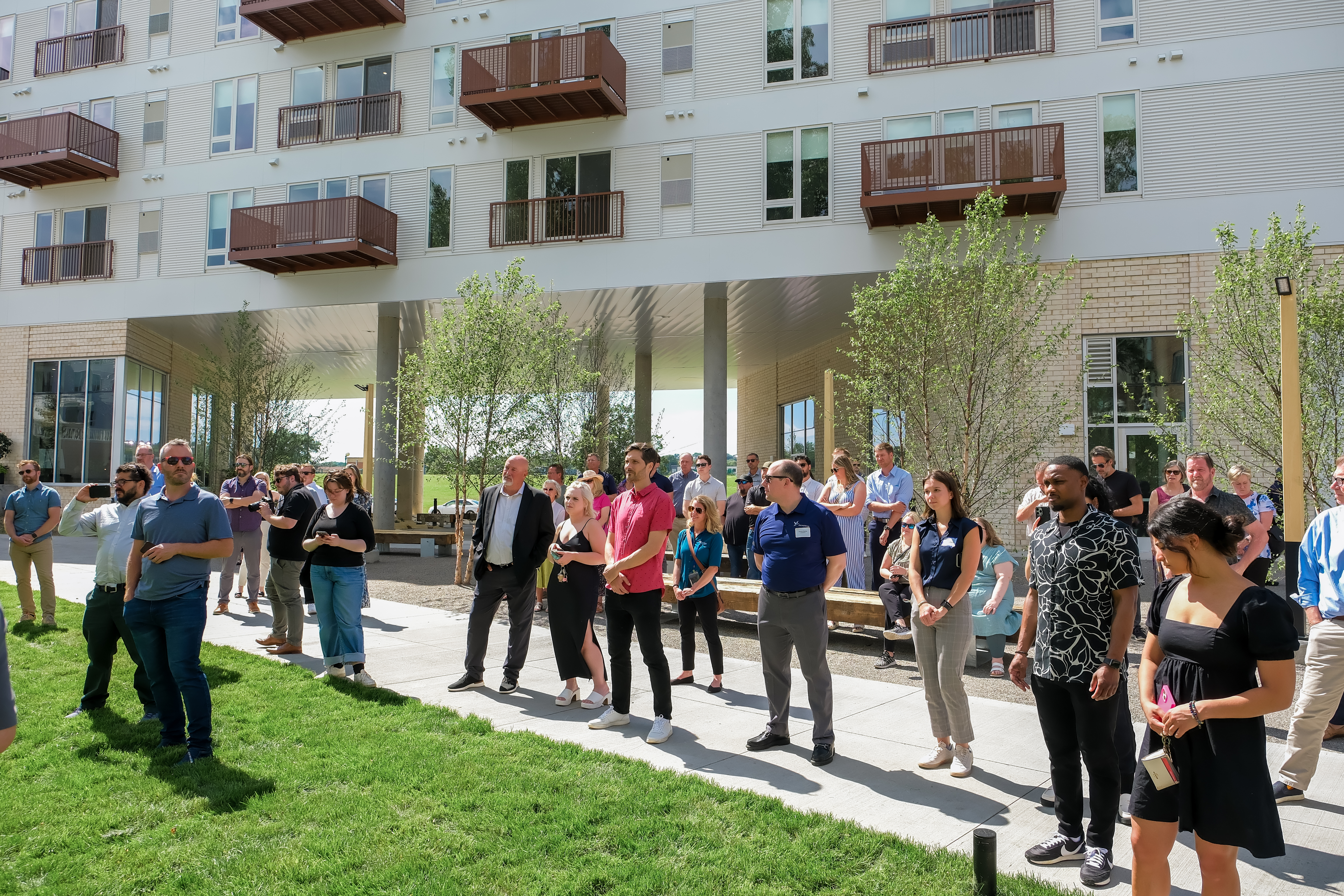 A crowd of people at an event in the courtyard of an apartment building.