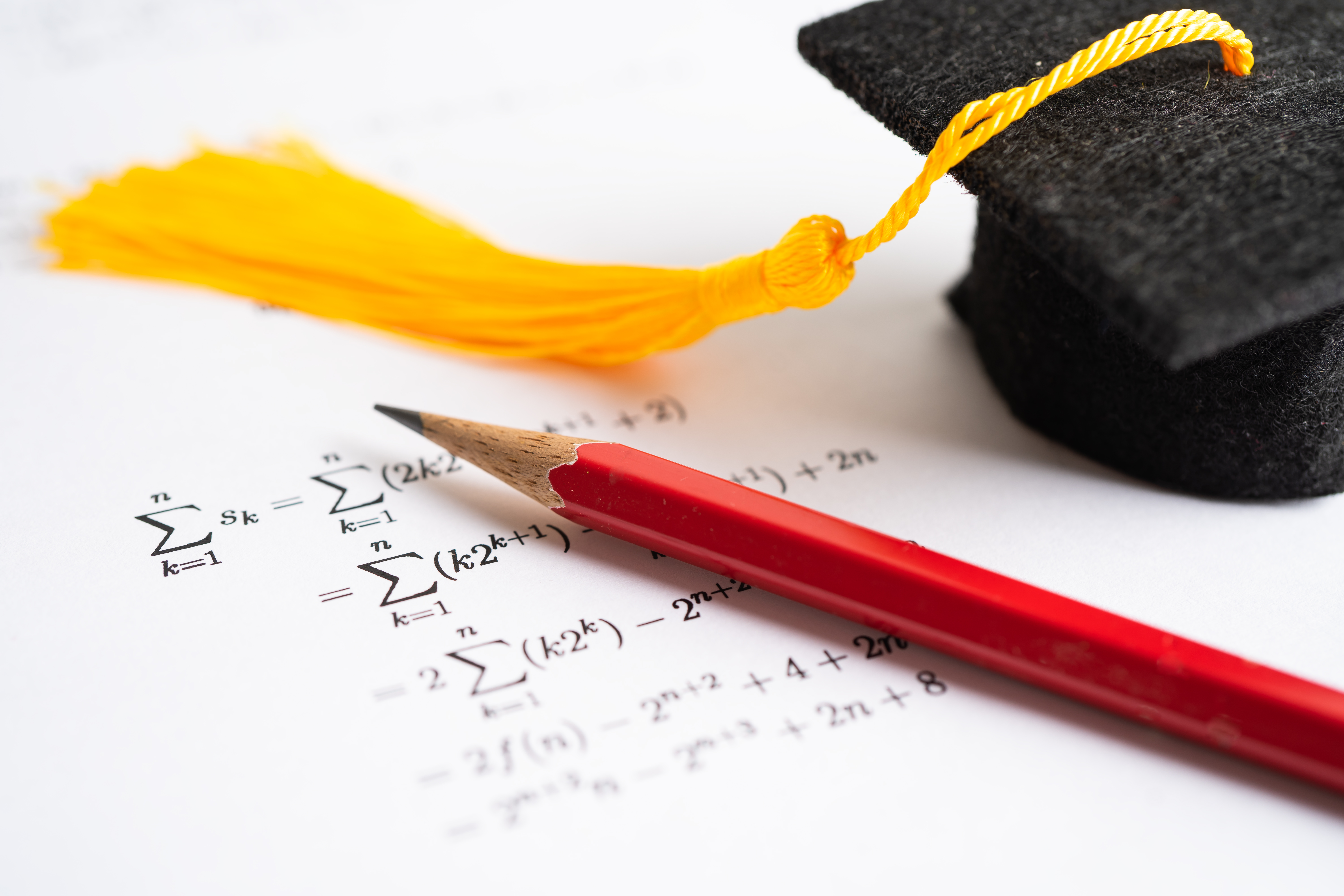 Graduation cap with a pencil and paper studying math