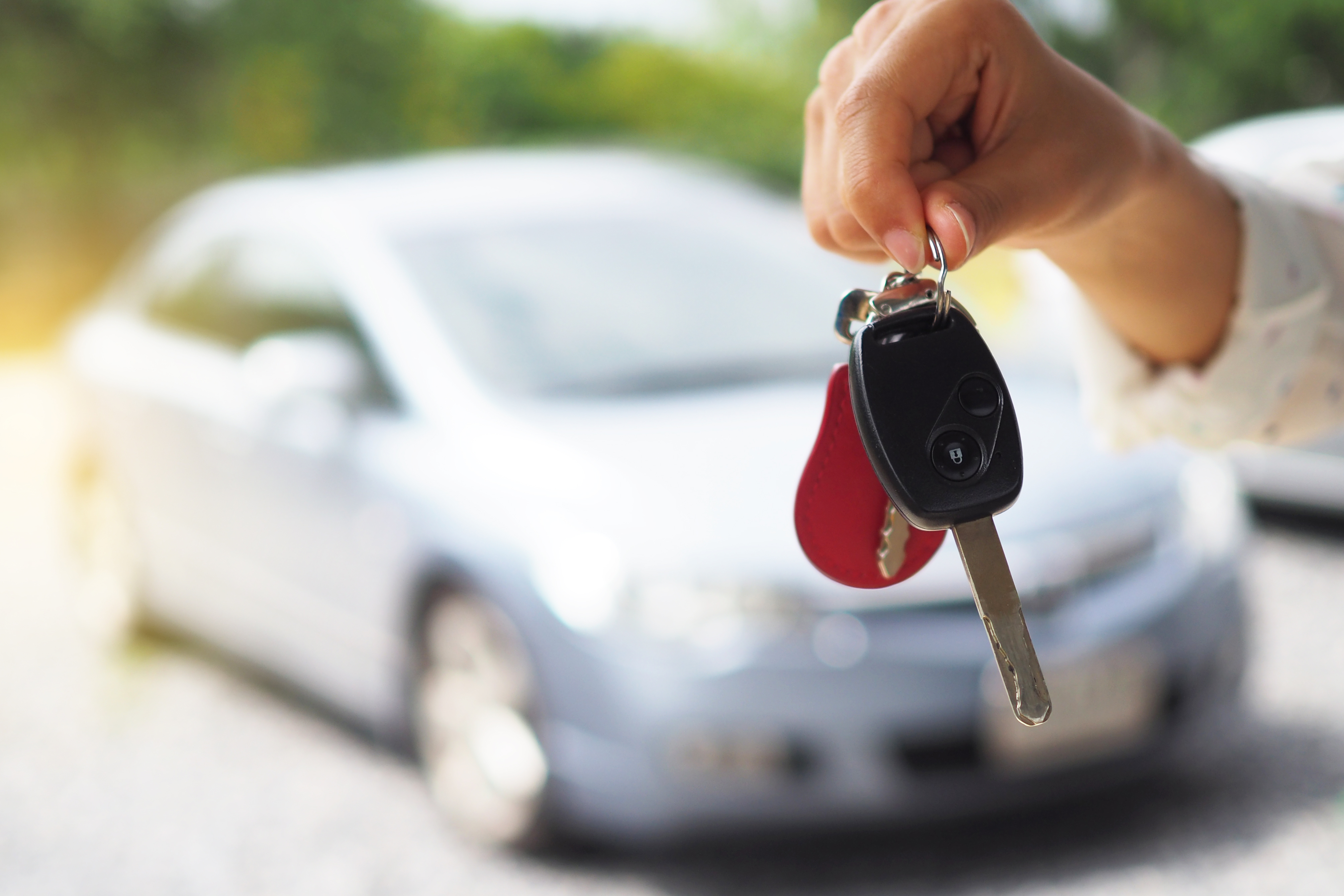 Person holding car keys in front of a car