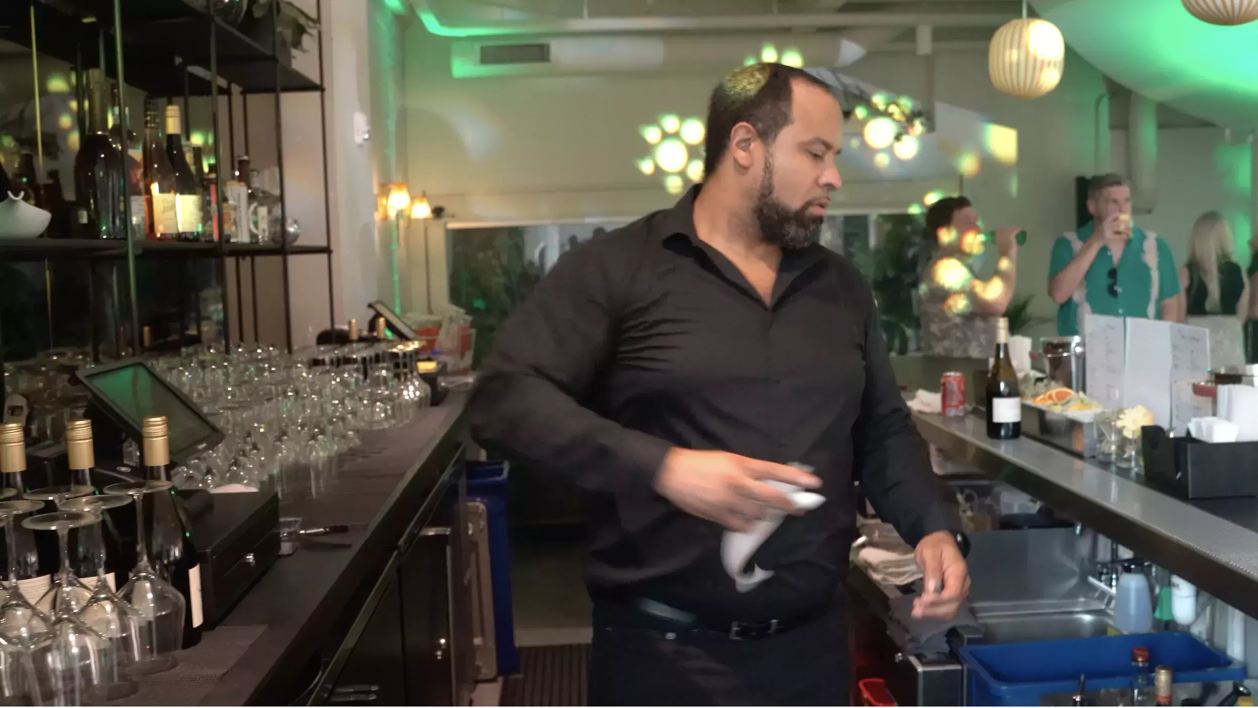 A bartender turns away from a cash register to provide a receipt to a guest.