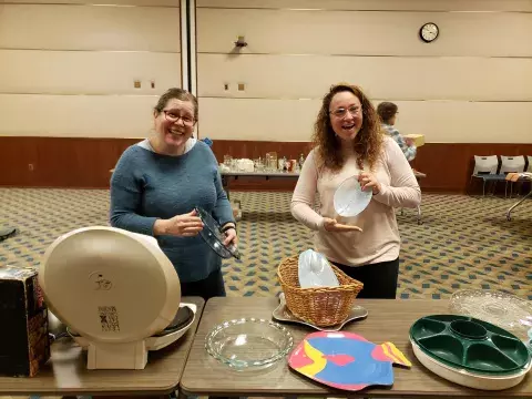 2 women showing items that they found at a swap event