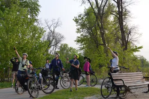 People take a break from a bike ride through a park to look for birds with binoculars.