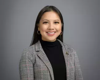 Photo of Ward 6 Councilmember Nelsie Yang smiling in a black shirt and gray suit in front of a gray background. Photo credit: Rich Ryan.