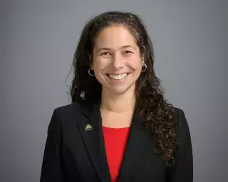 Photo of Ward 2 Councilmember Rebecca Noecker smiling in a red shirt and black blazer in front of a gray background. Photo credit: Rich Ryan.