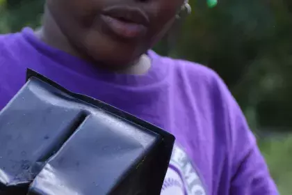 A girl takes a plant out of a black plastic pot