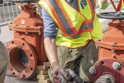 SPRWS lab staff collecting a water sample from a pipe